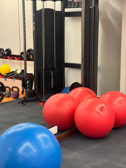 A corner of our gym area showing a variety of equipment, including stability balls, kettlebells, and a cable machine. We have the tools needed for a wide range of strength and conditioning programs.