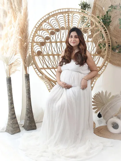 For the free-spirited mom-to-be, a boho-chic setup is perfect. The natural textures of the peacock chair and pampas grass complement the soft white gown, creating a serene and earthy portrait.