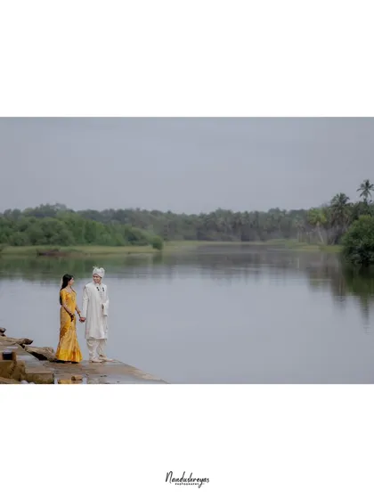 A minimalist wide shot of a couple by the river, with a large amount of negative space that creates an artistic and serene feel.