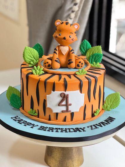 This jungle-inspired delight features a hand-modeled fondant tiger, textured stripes, and lush edible foliage. It's a wild and adorable cake for a child's birthday celebration.