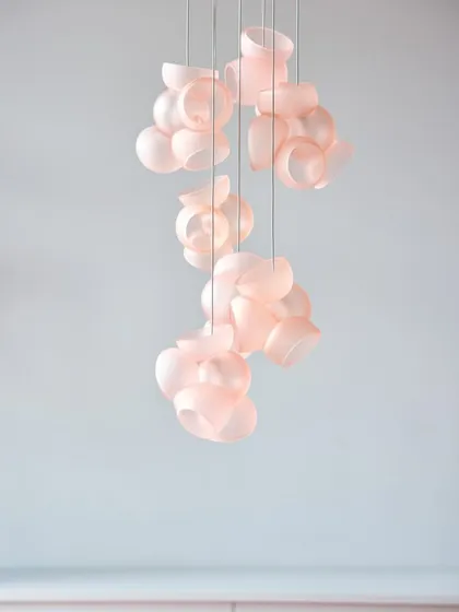 A cascading installation of the pink Bocci 100 series against a pale blue wall, creating a serene and beautiful color combination.
