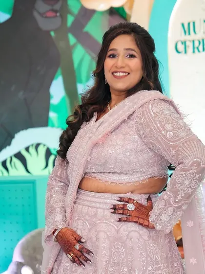 This client is celebrating a Mundan ceremony. Her lavender lehenga is paired with soft, shimmery makeup and loose curls for a pretty and festive look.