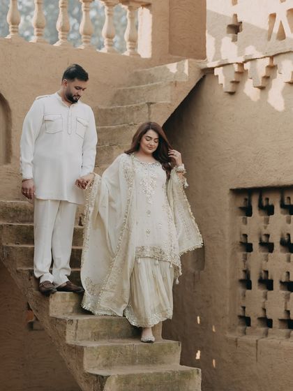 A couple descends the steps of a traditional mud-brick house in Punjab. The earthy tones and traditional attire create a timeless and culturally rich pre-wedding portrait.