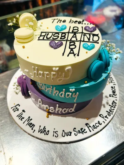 The other side of the three-tier husband's birthday cake, featuring a sweet tic-tac-toe game and a heartfelt message written around the base.