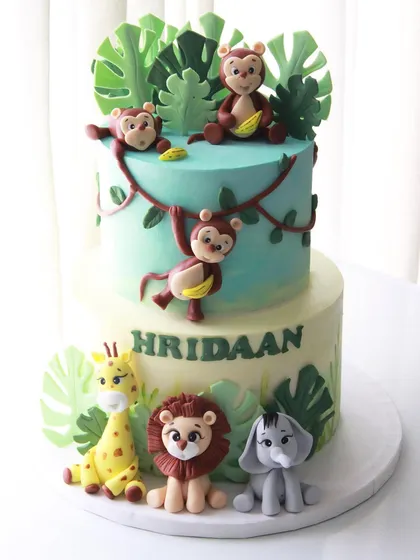 A two-tiered jungle theme cake for Hridaan's 1st birthday. I created a playful scene with monkeys swinging from vines and other friendly animals gathered at the base.