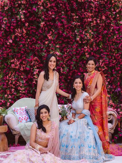 A bride and her bridesmaids pose against a stunning wall of bougainvillea. We love using natural floral installations to create breathtaking and memorable backdrops for wedding photos.