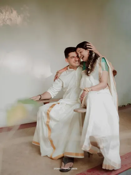 A playful and joyful moment, the bride laughing as she sits on her groom's lap.