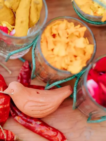 A detail shot of the spices and flower petals used in the decor, including dried red chilies and fresh turmeric, engaging all the senses.