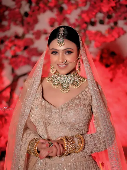 We love capturing the genuine smiles and happy moments. This portrait of a bride in a beautiful pastel lehenga against a vibrant red floral background shows how we blend candid emotion with a perfectly styled shot.