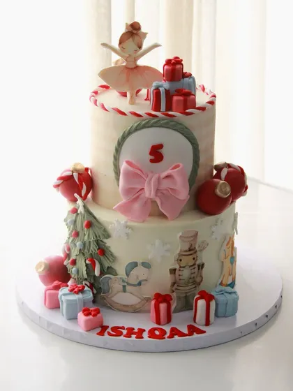 A very merry 5th birthday! This Christmas-themed cake is a festive delight, featuring a ballerina, nutcracker, rocking horse, and lots of presents, all handcrafted with holiday cheer.
