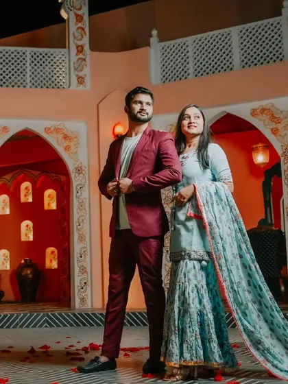 A powerful, upward-looking pose that conveys a sense of shared dreams and aspirations. The couple stands together in a beautifully lit, ornate setting.