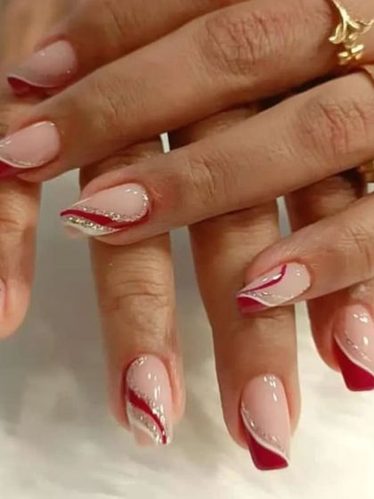 A sophisticated design with a nude base, red abstract swirls, and a delicate line of silver glitter.