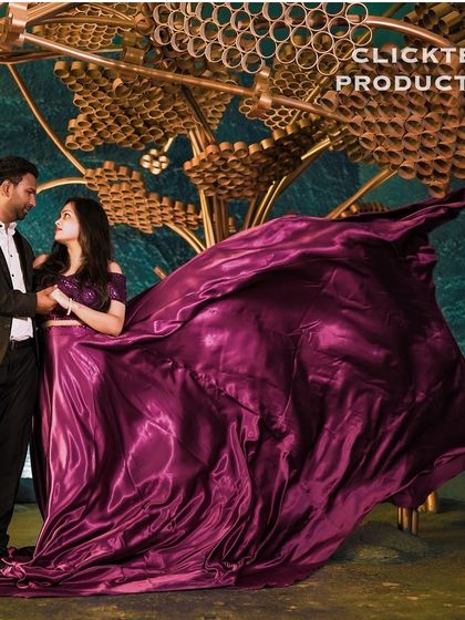 A dramatic shot of a couple with a flowing magenta gown against a unique, artistic backdrop, showcasing a creative and modern pre-wedding style.