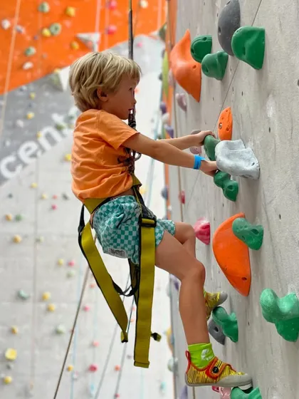 This young climber is suspended mid-climb, fully engaged in the challenge. It's a great way to build physical strength and mental focus.