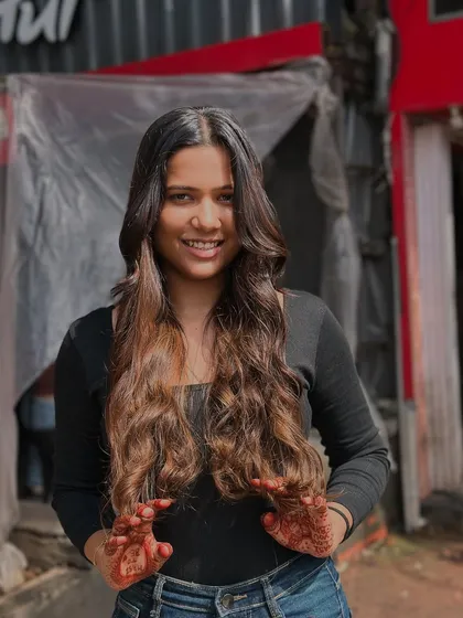 A beautiful, smiling portrait of a client loving her fresh balayage and waves.