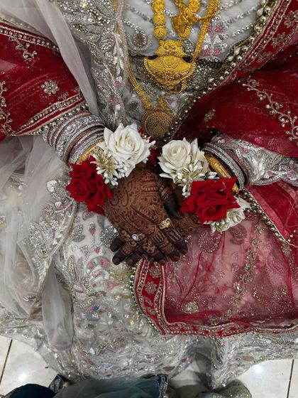 The bride's hands, adorned with her engagement rings and floral bracelets, showcasing the beautiful, dark henna stain.