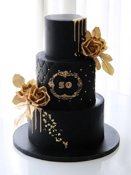 A closer look at the details on this black and gold 50th birthday cake. The combination of a quilted texture, gold drip, and handcrafted sugar roses creates a truly luxurious feel.