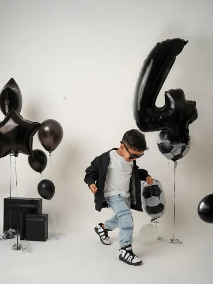 Another playful moment from the fourth birthday shoot, as he interacts with the football-themed balloons. These sessions are all about movement and fun.