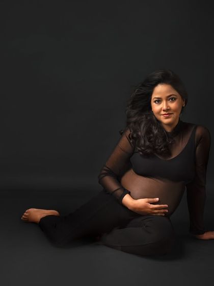 A simple, beautiful portrait in a sheer black top, focusing on the direct connection and the mama's confident smile.