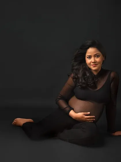 A simple, beautiful portrait in a sheer black top, focusing on the direct connection and the mama's confident smile.
