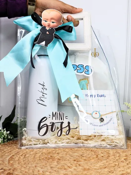 A full view of the "Boss Baby" Rakhi hamper, showing the "Mini Boss" water bottle and custom cap, presented in a clear bag with a "Boss Baby" tag.