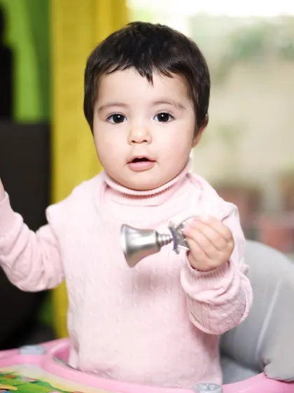 Playing with a toy bell in her walker. These candid photos capture the simple joys of playtime and preserve authentic childhood memories.