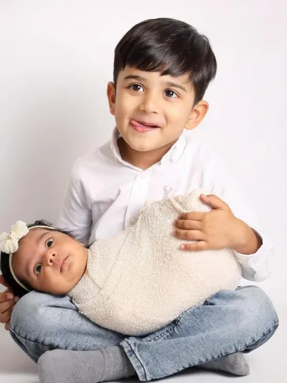 Capturing the real, playful moments is what I do best. A big brother makes a funny face while his alert newborn sister looks on, showing the fun side of sibling photos.