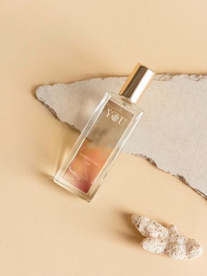 A flat-lay composition of Yot perfume with textured paper and coral. This artistic approach is perfect for creating a mood board or theme for a brand's social media feed.