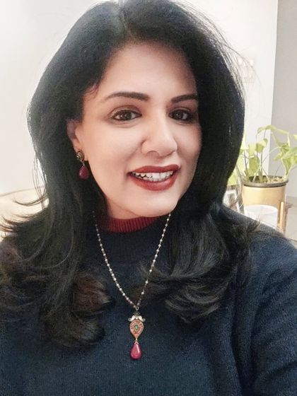 A close-up of the ruby and kundan pendant set. The warm tones of the jewelry complement the colours in the tartan skirt, creating a cohesive and festive ensemble.