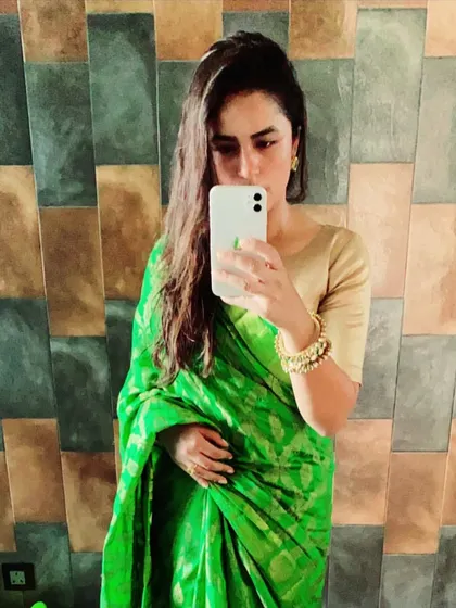 A vibrant green Banarasi silk saree is a wardrobe essential for its rich color and traditional weave. In this mirror selfie, you can see how it drapes beautifully, making it a go-to for any festive celebration.