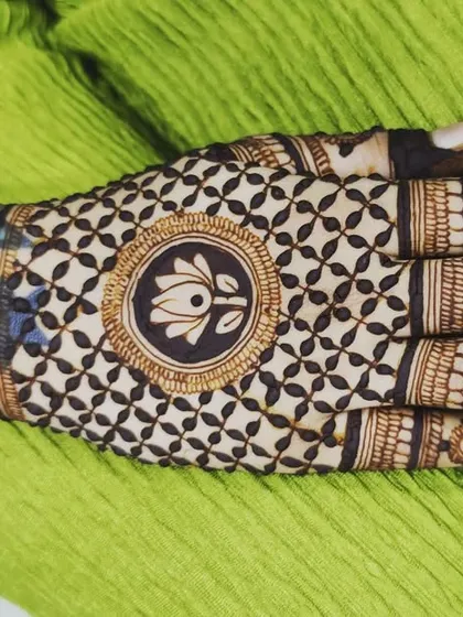 A designer back-hand mehndi with a central lotus mandala. The checkerboard pattern, or jaali, is a classic element that always looks elegant.