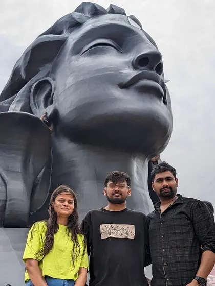 Three travelers posing in front of the Adiyogi statue.