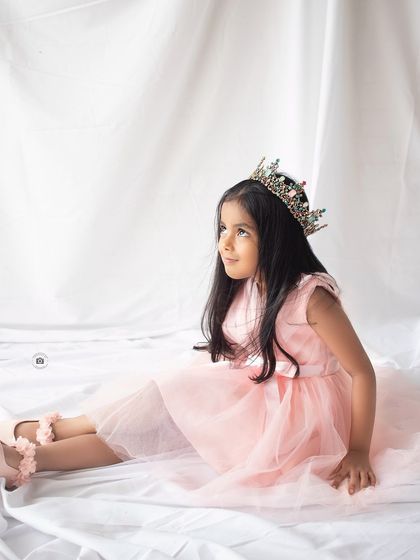 A princess moment for her fifth birthday. Wearing a beautiful crown and a soft pink dress, she looks thoughtful and serene.