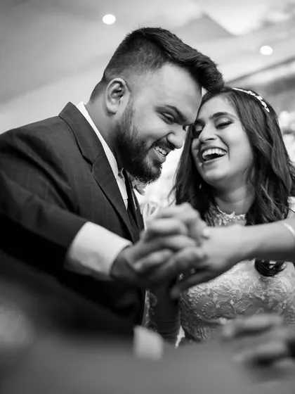 A beautiful candid moment of a couple surrounded by the hands of their loved ones. This black and white photo is framed to draw you into their shared laughter and joy.