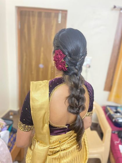 The braid adorned with fresh red roses.