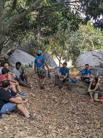 An instructor leads a debrief session under the trees. We focus on teaching not just the 'how' but also the 'why' behind climbing techniques and safety.