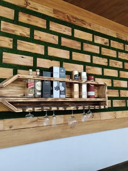 This custom-built bar unit is a great example of my bespoke woodwork. The main feature is the bottle-shaped shelf with integrated wine glass holders, set against a backdrop of reclaimed wood blocks and artificial turf for a unique, textured look.