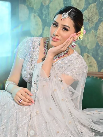 A modern bridal glam look where less is more. The focus is on clean lines, glowing skin, and eyes that speak volumes, paired with a stunning silver lehenga and ruby jewelry.