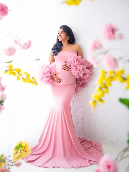 As pretty as pretty can be. This mamma is glowing in a pink gown, framed by beautiful flowers against a clean white brick wall.