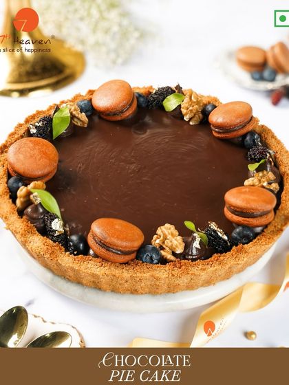 Our Chocolate Pie Cake is a true indulgence. It has a buttery crust, a rich chocolate filling, and is elegantly decorated with macarons, walnuts, and berries.