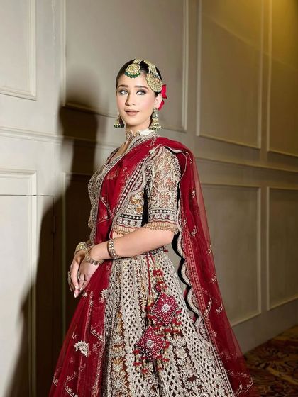 A full-length view of a bride in a multi-toned heritage lehenga, combining shades of red and brown.