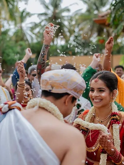 The pure, unscripted joy of a wedding ceremony. We live for these candid moments, where the bride's radiant smile is showered with blessings and flower petals, creating a memory filled with genuine happiness.