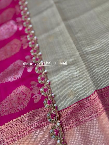 A close-up of a scalloped border with pink and gold embroidery, adding a rich finish to this silk saree.