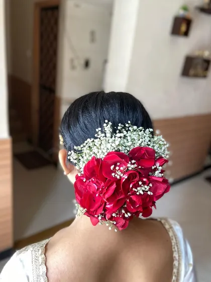 The classic bridal bun, perfected. I used fresh red roses and delicate baby's breath to create this rich, elegant hairstyle, a timeless choice for any traditional wedding ceremony.
