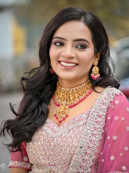 A close-up portrait that beautifully captures the bride's smile and the intricate details of her gold temple jewelry.