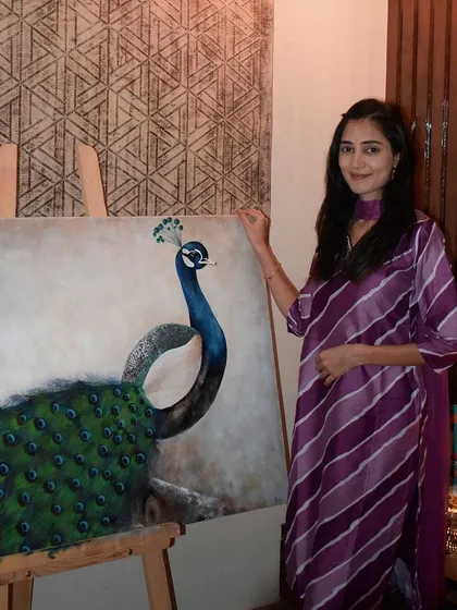This is me with a finished peacock painting, a piece that took hours of patience, paint, and good music to complete. It’s a joy to stand next to a finished canvas that started as just a blank space.