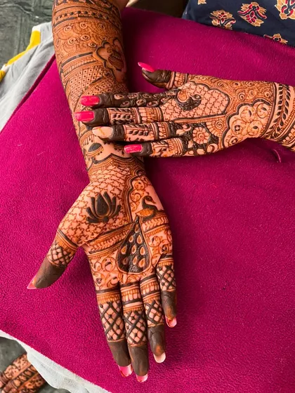 A close-up of the palm, featuring a lotus and peacock design. The fine lines and detailed shading showcase the quality of the artistry.