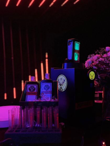 A dedicated Jägermeister station, complete with a branded dispenser and test tube shots, all illuminated by the dramatic red and blue lights of the neon theme.