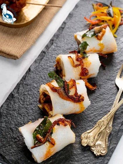 A closer look at my Chicken Gassi Rolls, wrapped in a soft rice crepe and topped with crisp fried onions and curry leaves. This dish is a modern interpretation of a traditional coastal flavor.