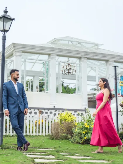 A playful, long-distance shot in a garden with a beautiful glasshouse in the background. The composition creates a sense of story and anticipation.